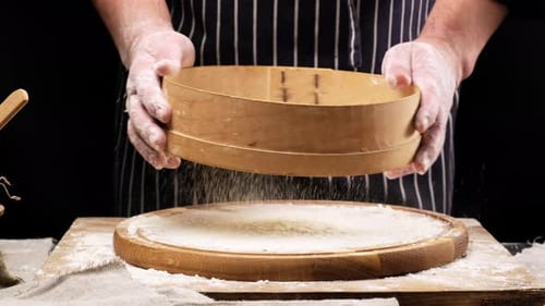Baker Sifting Flour onto Wooden Cutting Board