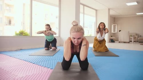 Three Women Having Yoga Classes in the Bright Studio the Older One Stands in the Front and All of