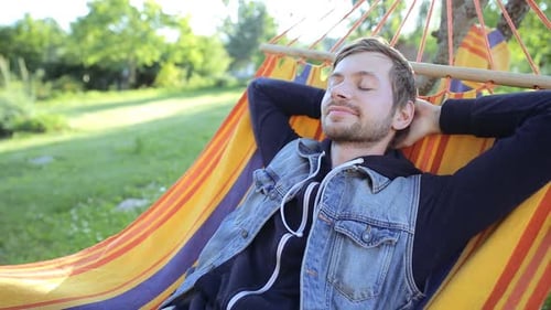 Young Happy Man Relaxing In Hammock At Garden