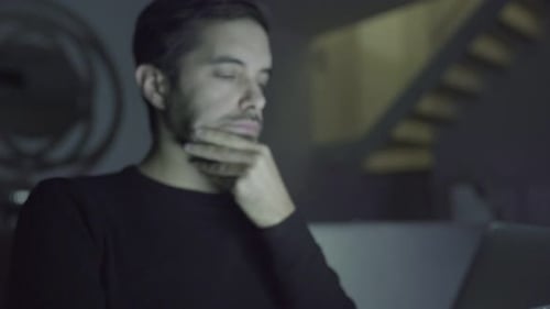 Focused Man Using Laptop Late at Night Indoors