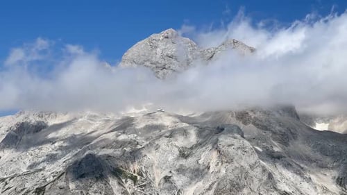 Majestic Mountain Peaks Shrouded by Clouds on Sunny Day