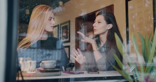 Zwei hübsche Mädchen entspannen sich und unterhalten sich und trinken Kaffee im Café