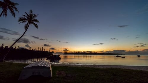 Small boats move with the current on a secret bay, Isle of Pines. Day to night timelapse.