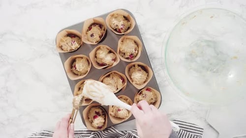 Flat lay. Step by step. Scooping dough into tulip muffin liners with mixture scoop to bake cranberry