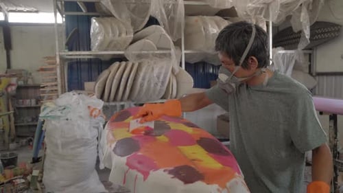 Handwerker malen Surfbrett mit verschiedenen Farben