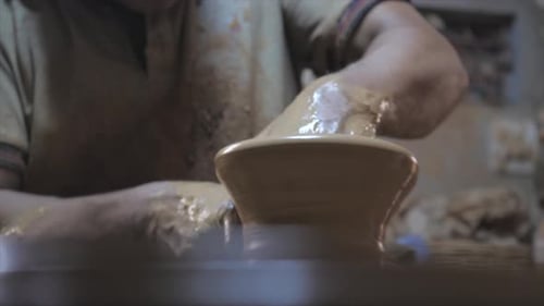 Close up view of potter shaping clay vessel on the potters wheel.