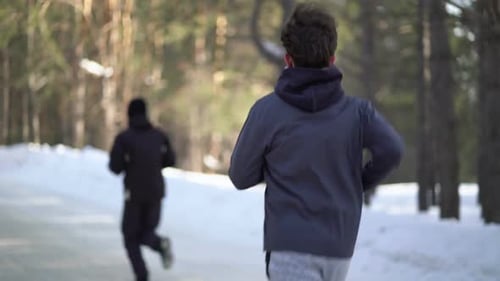 People Running in a Snowy Forest in Winter
