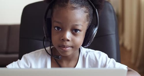 Close-up Portrait Afro American Little Girl Daughter Child Sitting at Laptop Wears Head Microphone