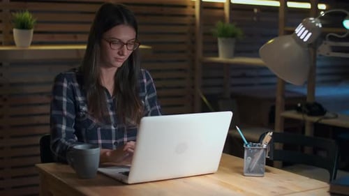 Woman Working on Laptop at Wooden Desk Indoors