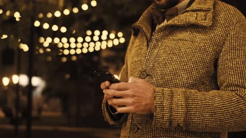 A Man in a Shirt Holds His Mobile Phone in His Hand and Quickly Swipes His Finger Across the Screen