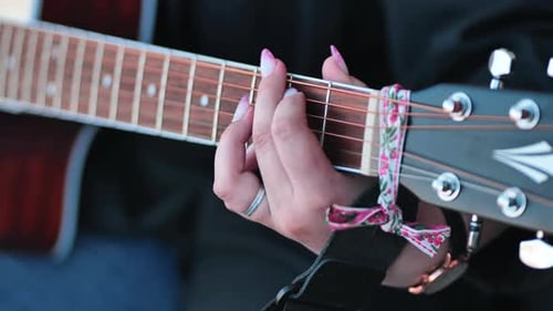 Woman plays guitar chords close up detail