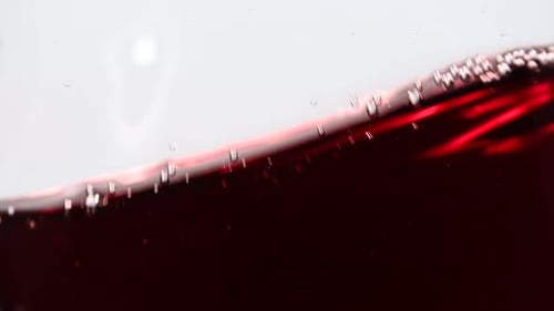 Close up swirling red wine in wineglass over white