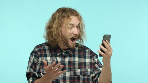 Man Reacts to News on His Phone with Surprise