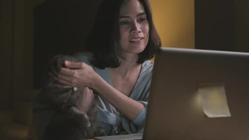 Woman Working at Home Holding Cat in Arms
