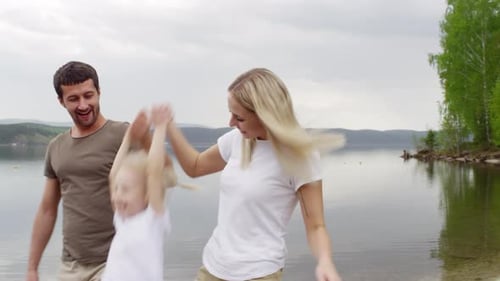 Happy Family of Three Enjoying Walk by the Lake