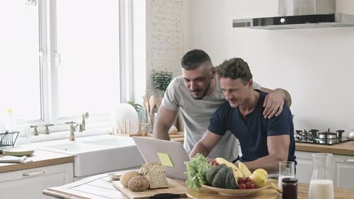 Two Men Working on Laptop in Kitchen
