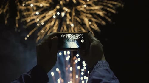 Person Recording Festive Fireworks Display at Night