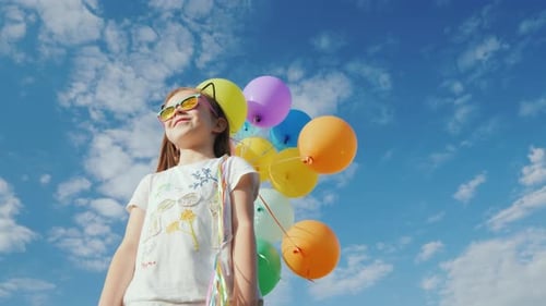 Happy Child Smiling with Colorful Balloons Under Blue Sky