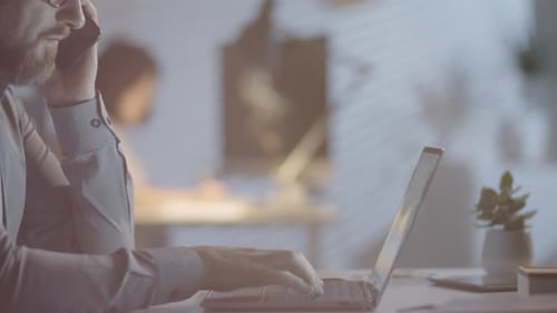 Man Working in Dark Office and Talking on Phone