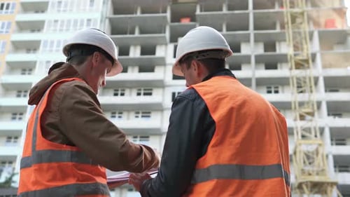 Construction Workers Discussing Blueprints on Building Site