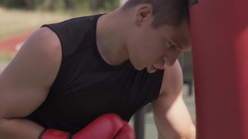 Man Training with Punching Bag Outdoors on Sunny Day