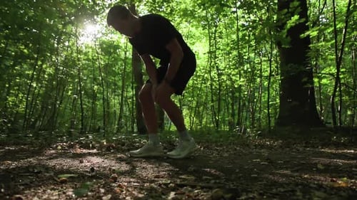 Injured Runner Holding Knee in Sunny Green Forest
