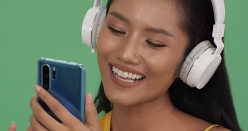 Woman with Headphones Listening to Music on Phone