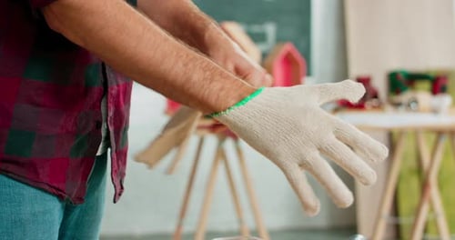 Man putting on work gloves in workshop
