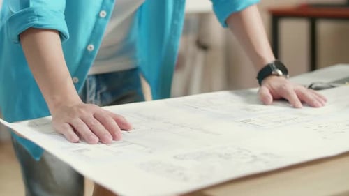 Close Up Of Asian Man Engineer With A Laptop Looking At Blueprint While Working At The Office
