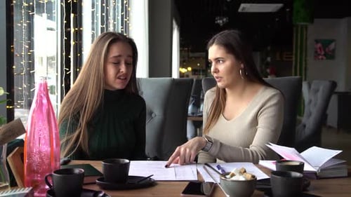 Women Discussing Documents at an Urban Cafe Table