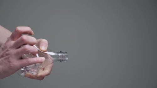 Hands Squeezing Empty Plastic Bottle for Recycling