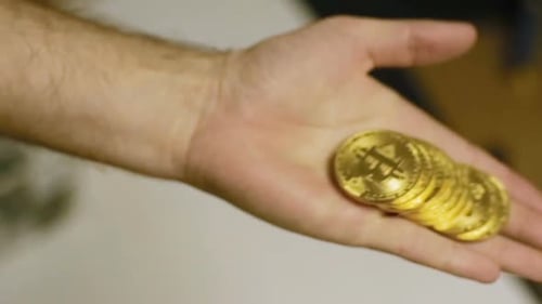Hand Holding Golden Bitcoin Coins Close Up