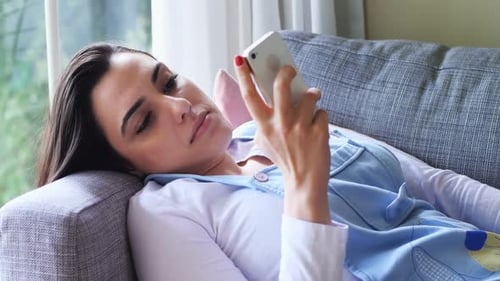 Woman Using Phone Relaxing on Couch at Home