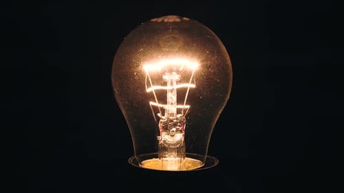 Light Bulb Starts Glow At Night. Dirty Filament Lamp Glass With Scratches Evokes Horror. Bright Glow