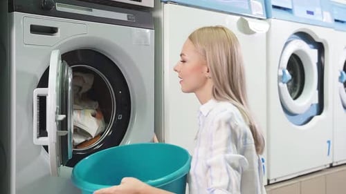 Woman Unloads Towels from Washing Machine in Laundromat