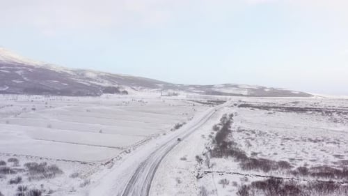 Luftaufnahme des Autos, das im Winter durch die verschneite Straße fährt.