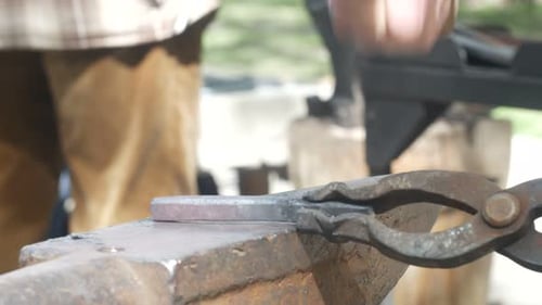 Blacksmith Shaping Hot Metal with Hammer and Anvil