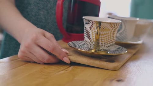 Woman Takes Board with Cups and Teapot From Table Close View