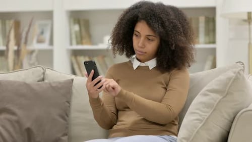 Woman Using Smartphone on Couch in Bright Living Room
