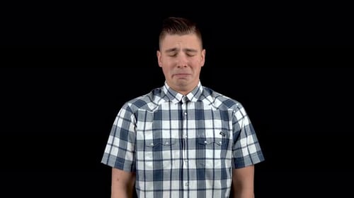 A Young Man Shows an Emotion of Sadness. Sad Man in a Shirt on a Black Background