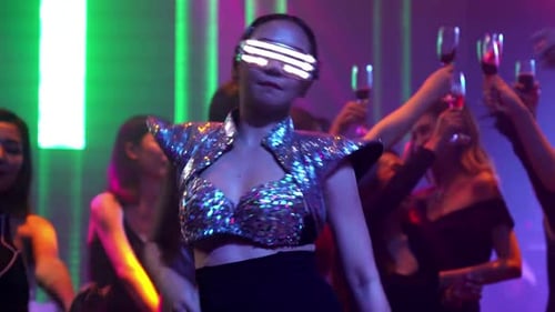 Eine Gruppe von Menschen tanzt im Disco-Nachtclub zum Takt der Musik eines DJs auf der Bühne