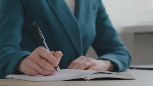 Woman Writes in Notebook at Desk