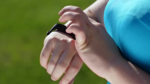 Woman Taps Fitness Tracker in Nature