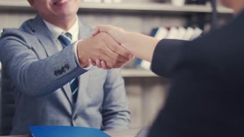 Asian businessman shaking hands partnership deal business while standing indoors in the office.