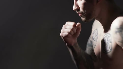 Entraînement masculin tatoué fort de boxe Muay Thai avant le combat dans la salle de gym au ralenti