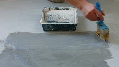 Person priming Cement Floor with a Brush