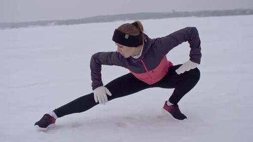 Woman Stretches on Snow-Covered Field in Winter