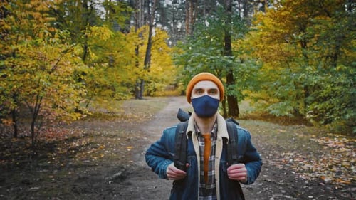 Man Hikes in Colorful Autumn Forest Wearing Face Mask