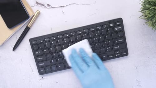Hand Cleaning Keyboard at Workspace with Wipe