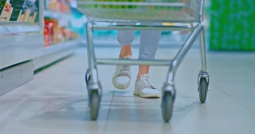 Closeup Women's Feet in Sneakers Walking Through the Supermarket